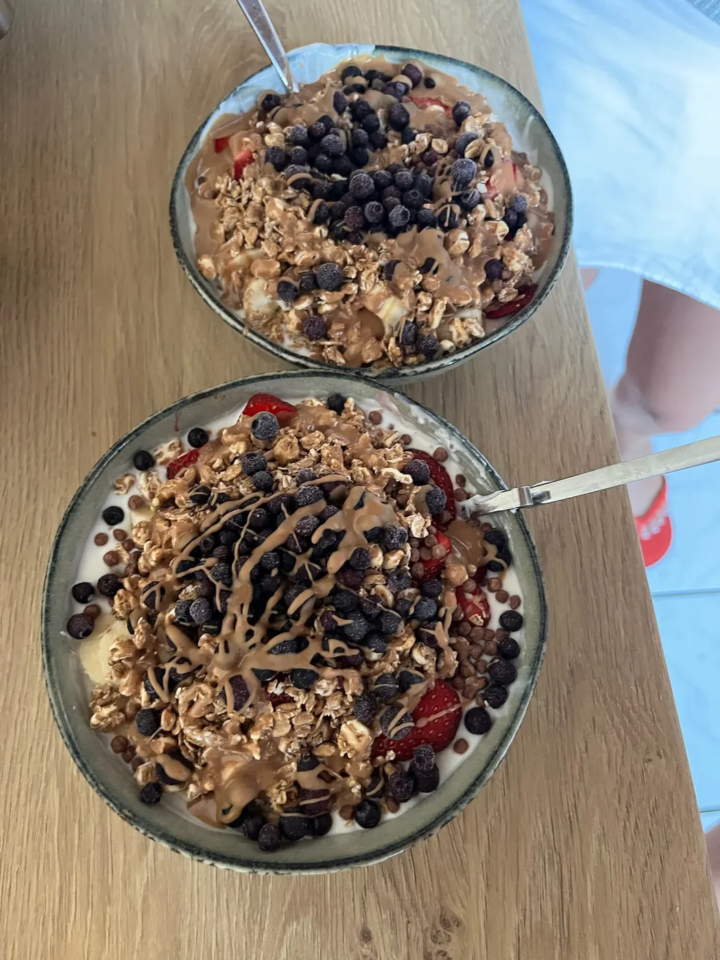 Zwei Joghurt-Bowls mit Granola, Beeren und Mandelmus