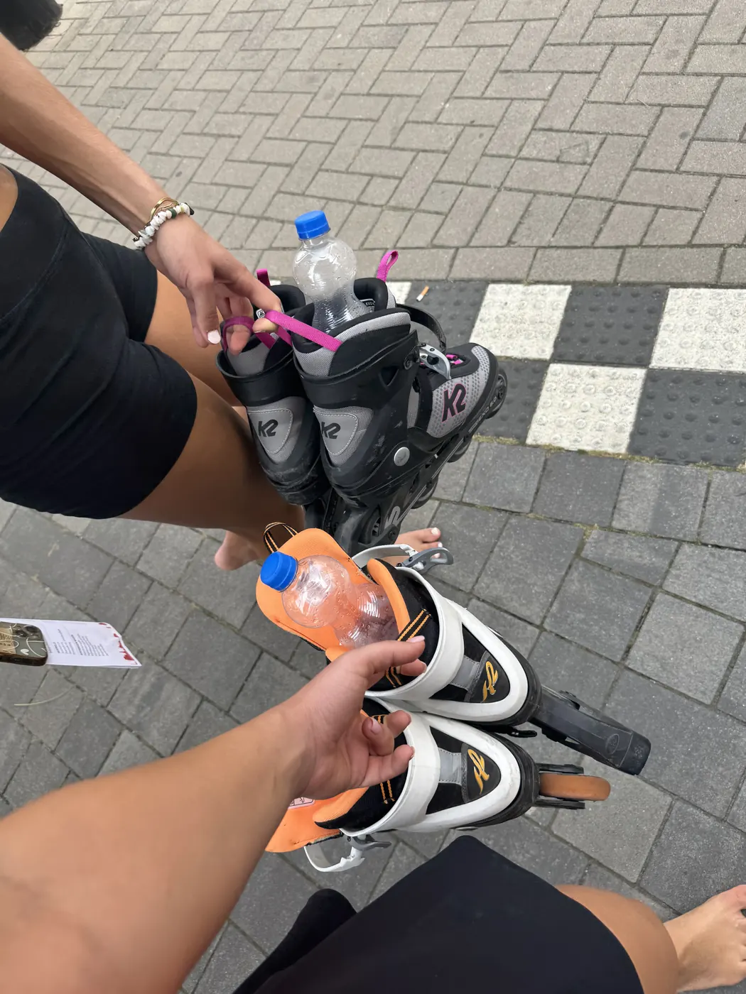Inlineskates in der Hand auf dem Gehweg